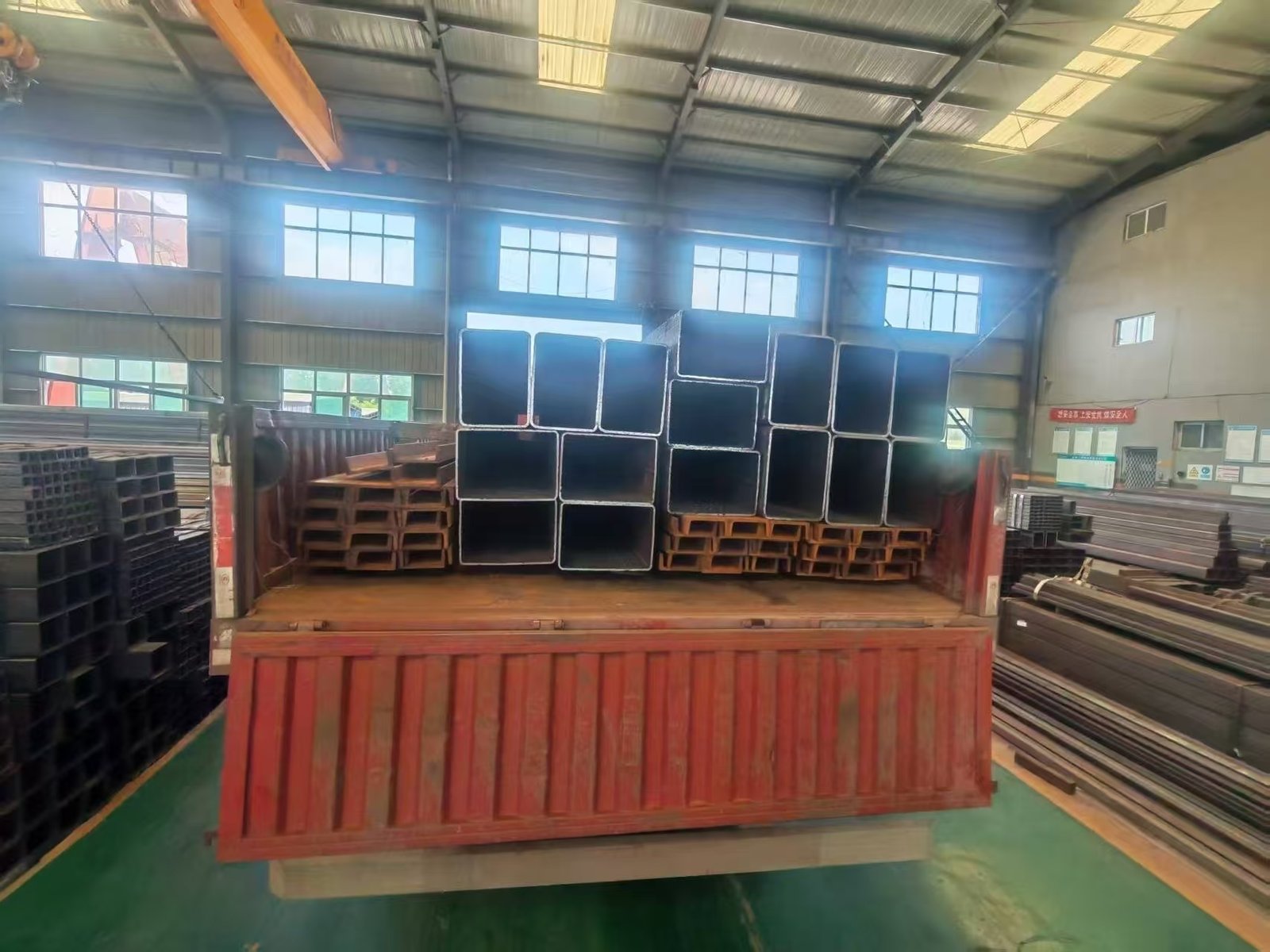 Packed square and rectangular steel tubes strapped on a flatbed truck ready for port delivery.