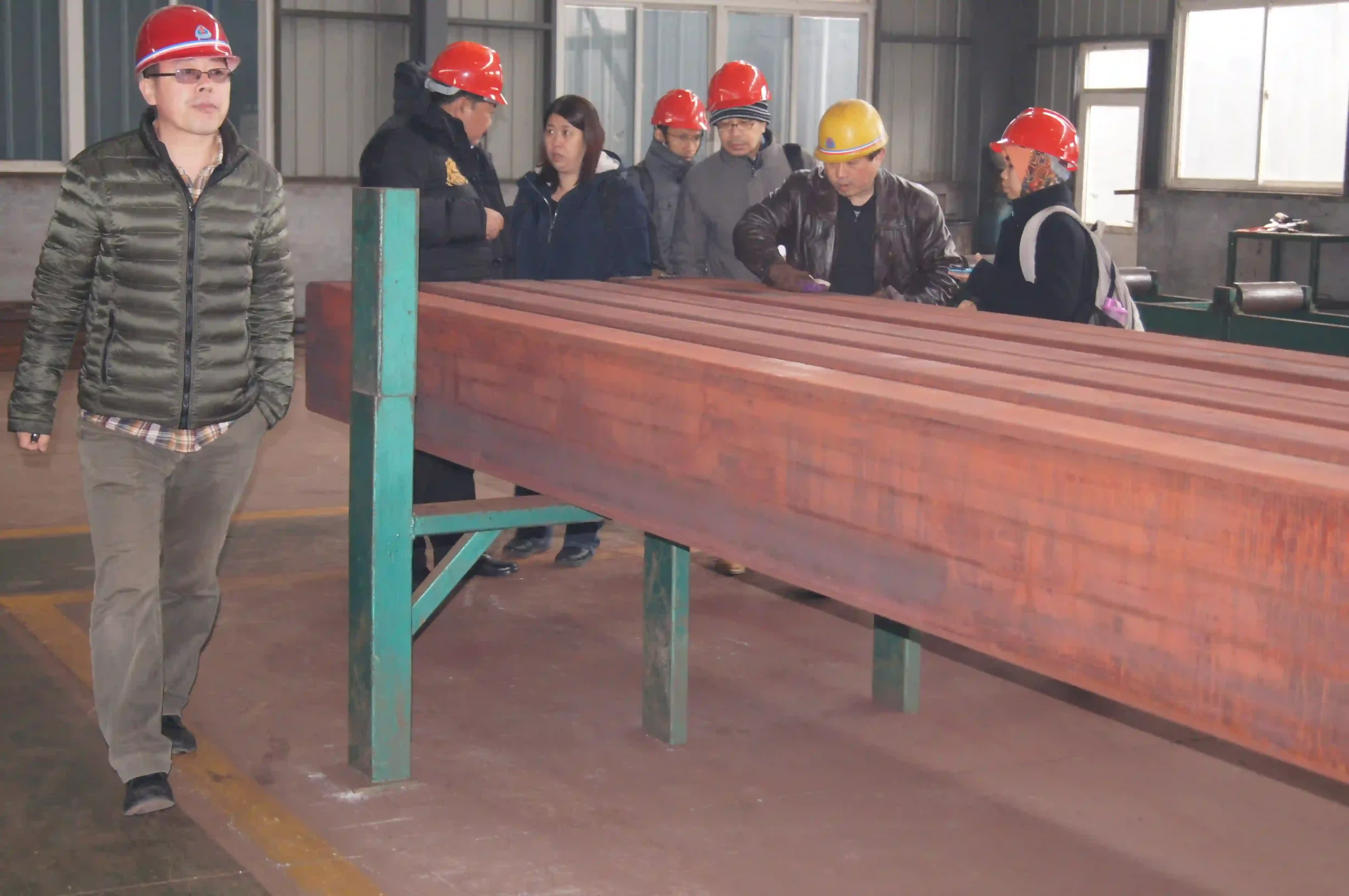 Buyer checking surface quality and marking of galvanized steel pipes before loading.