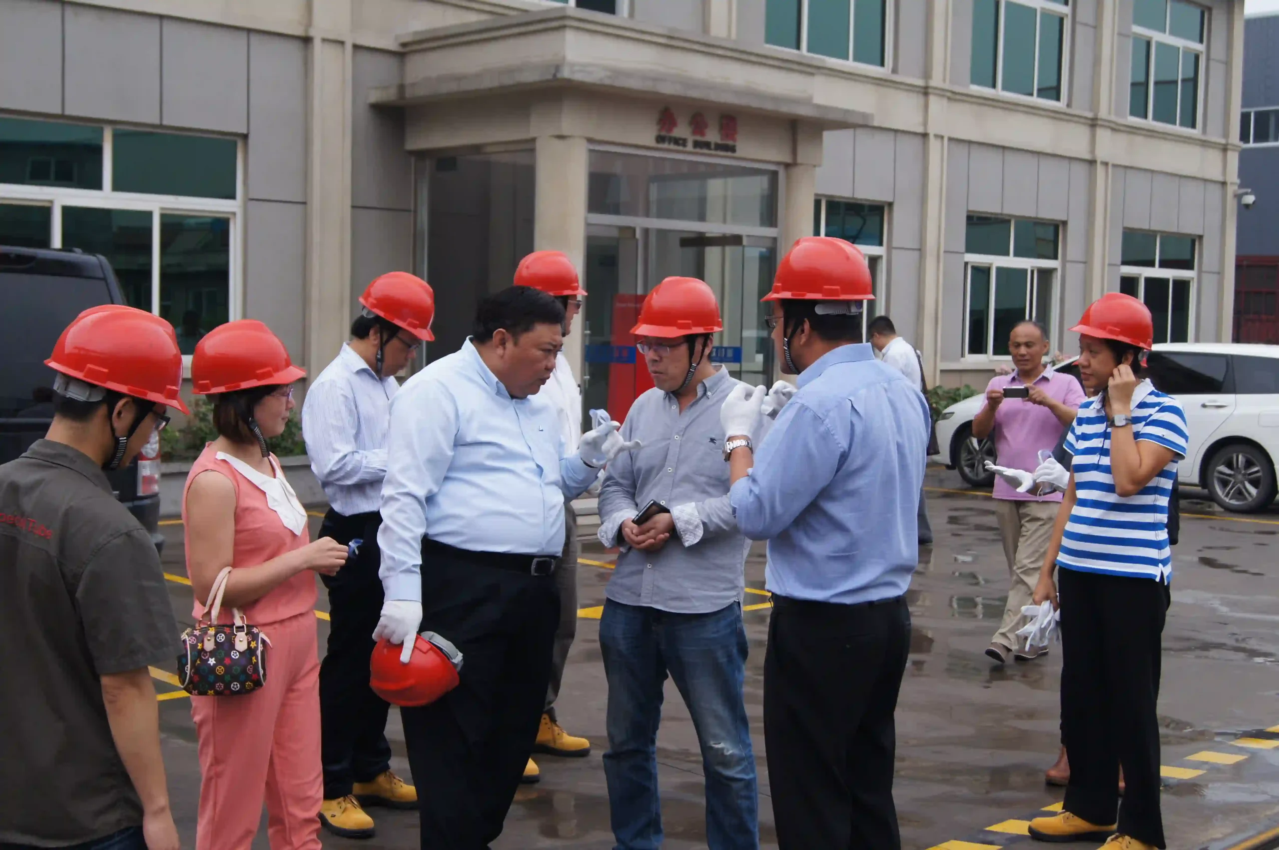 Group photo of an overseas delegation and the SD XJY Steel team at the factory entrance.
