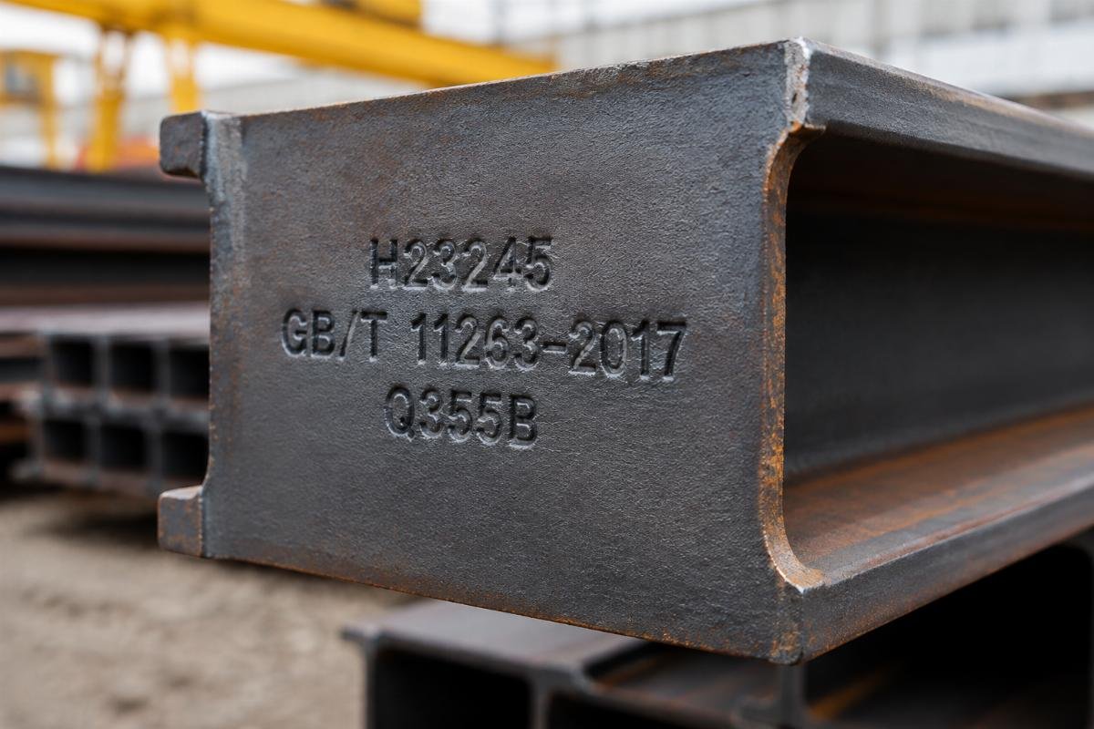 Close-up of a steel beam end showing stamped heat number and standard designation