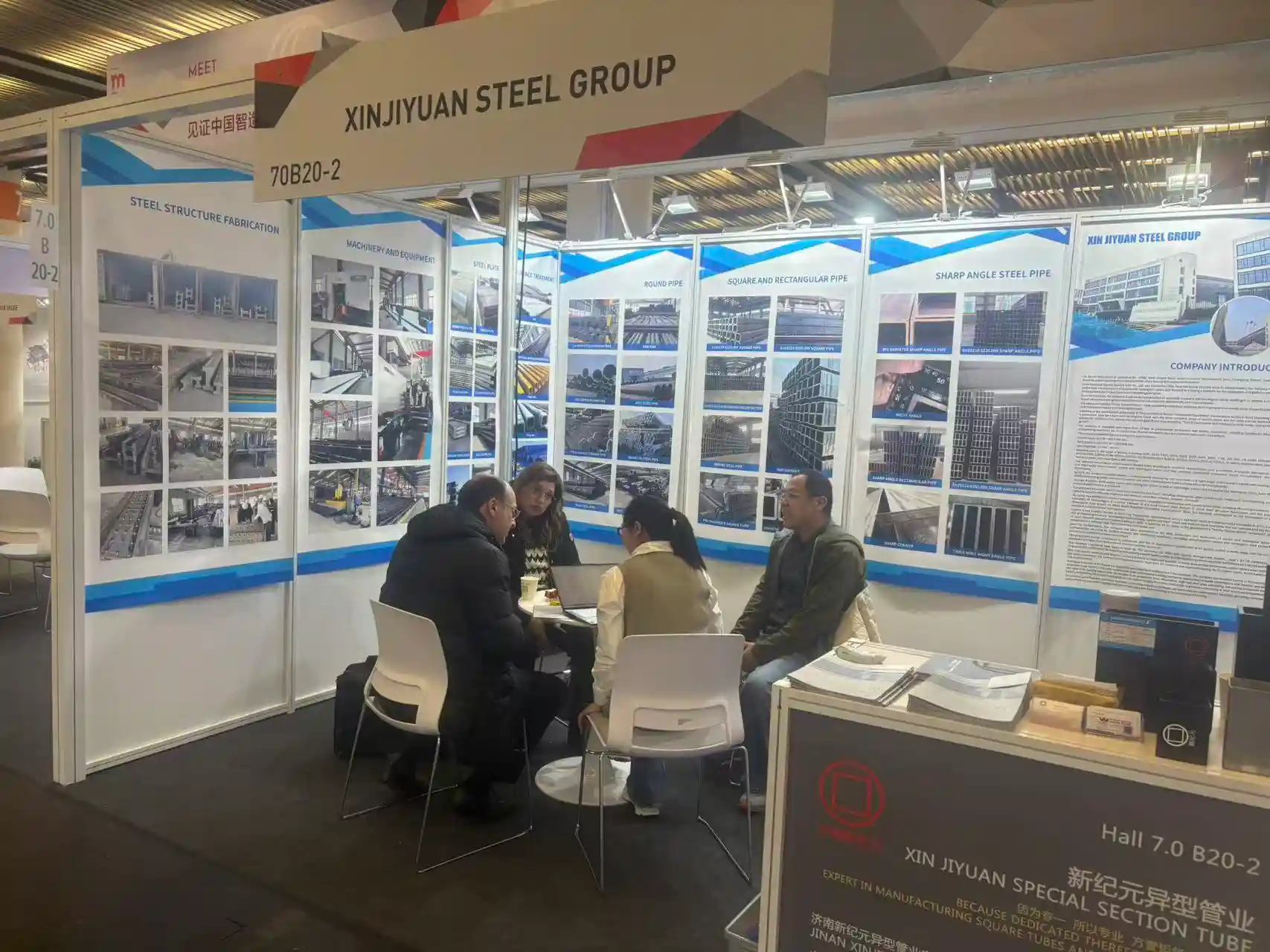 Sales engineers discussing steel specifications with visitors at a trade fair.